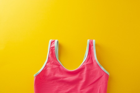 Creative flat lay of beach objects. Summer holidays minimalist style concept. Yellow background with pineapple mason jar juice, pink swimsuit, swim glasses, Copy spaceの写真素材