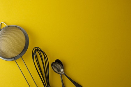 Baking tools for pastry or dessert sieve, whisk, spoon. Yellow background, flat lay. Cooking process. Copy space.の写真素材