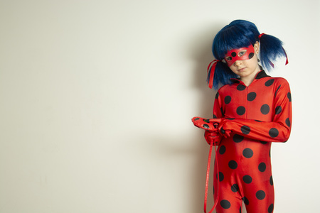 Corby, United Kingdom. March 12, 2019 - little girl in Ladybug Myraculous cosplay costume. Superhero ladybug with blue twig, isolated.のeditorial素材