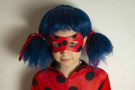 Corby, United Kingdom. March 12, 2019 - little girl in Ladybug Myraculous cosplay costume. Superhero ladybug with blue twig, isolated.のeditorial素材