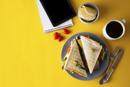 Snacks, fast food concept. Eatting at work place. Fresh club sandwich, vegetables, coffee, potato...
