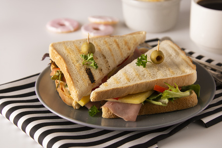 Stylish sandwich. Toasted double panini with ham, cheese fresh vegetables. Snack at work or lunch. Light background. Healthy food.の写真素材