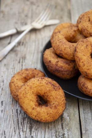Homemade donuts. round, circle delicious donuts in black plate, wooden background.の写真素材