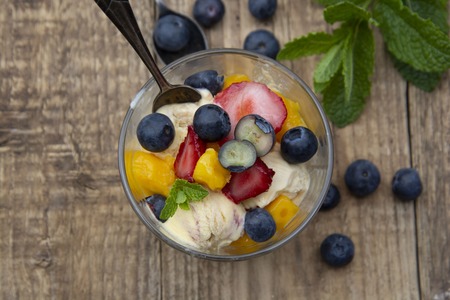 Fruit salad with ice cream - blueberries, strawberries, mango and mint, summer refreshing dessert....