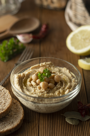 Homemade hummus. Woman hands with hummus in bowl, olive oil, lemon and spicesの写真素材