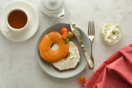 Breakfast with bagels and cheese, cherry, basil, tea cup. Healthy food, bright background.の写真素材