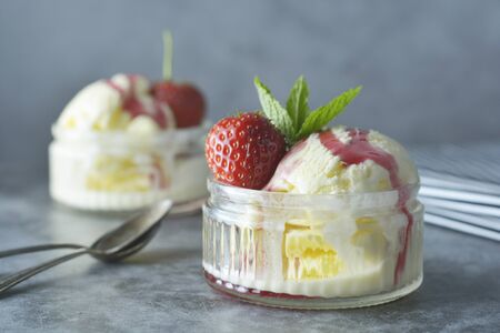 Delicious vanilla ice cream with mint leaves and strawberries, sweet dessert.