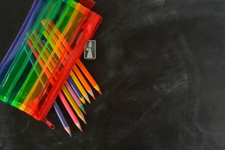 Back to school. Rainbow pencil case with school supplies for student. Black background.
