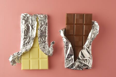 White and black chocolate bars over pink background, copy space, top view.の写真素材