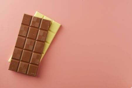 White and black chocolate bars over pink background, copy space, top view.の写真素材