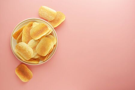 Crispy potato chips isolated over pink background. Flat lay.の写真素材