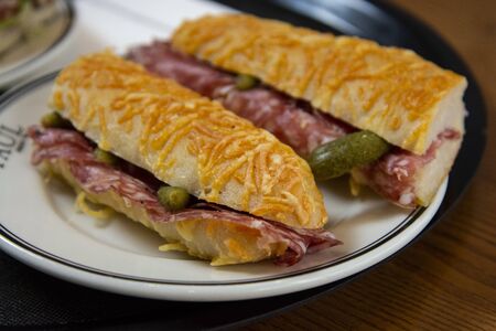 delicious baguette sandwich with ham and salami served on a plate in a bekery shop or cafe.の写真素材