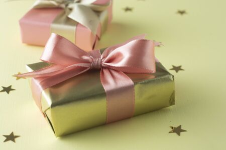 Golden and pink gift isolated on yellowの写真素材