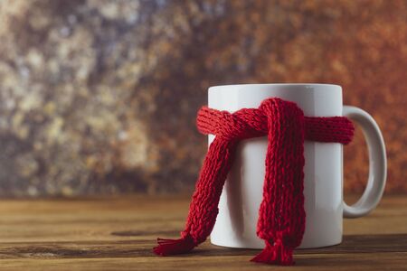 Tea cup of tea with red warm knitted scarf. Autumn, fall background. Cold and illness season. Copy space.の写真素材