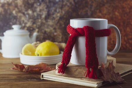 Ginger tea with honey and lemon. Tea cup with knitted red scarf. Autumn or winter warm drink. Wooden background, rustic style.の写真素材