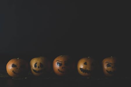 Happy Halloween citrus, tangerines painted with scary, funny faces. Dark photo with copy space for copy space.の写真素材
