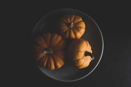 Three orange pumpkins autumn composition on black background. Halloween concept flat layの写真素材