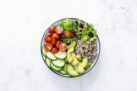 Healthy food in bowl with quinoa, avocado, cucumber, salad, tomatoes, olive oil Clean eating diet food.の写真素材