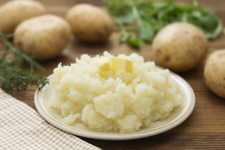 Mashed potatoes with butter and fresh white potatoes on background, wooden table. Healthy food.の写真素材