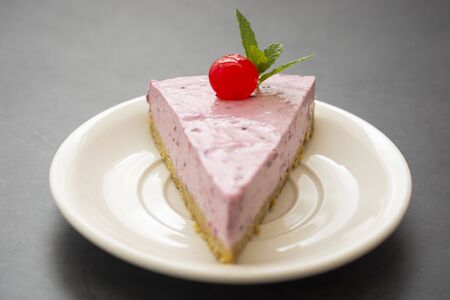 Cheesecake slice with berries, pink cheesecake isolated on dark background, dessert or breakfast.の写真素材