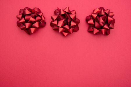 Red ribbon bows over red background, flat lay. Party, birthday, Christmas or Valentine's Day...
