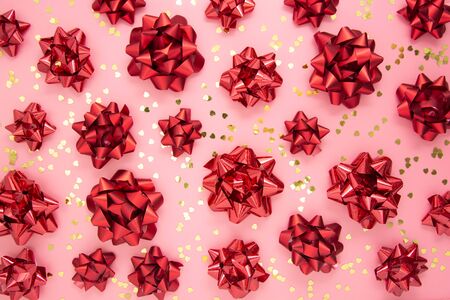 Red ribbon bows pattern, abstract pink background with golden glitter. Valentine's Day, Birthday, gift bow. Flat lay.の写真素材
