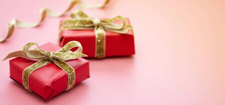 Red gift box and golden bow, on pink background. Valentine's Day, Birthday, Party concept. Mock up.