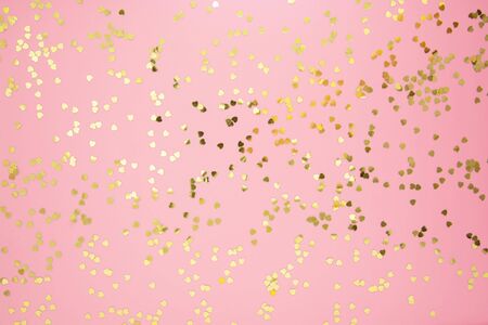 Abstract textured background, golden heart shape glitter over pink background. Valentine's Day, love, birthday, party concept. Flat lay with space for text.の写真素材
