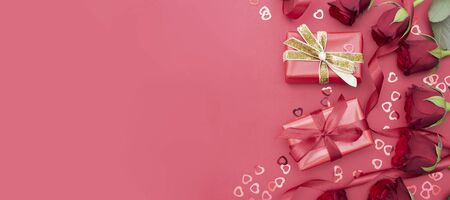Valentine's Day, red roses and gift box with ribbon, over red background flat lay, birthday abstract...