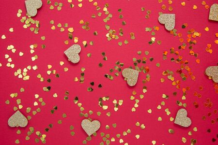 Love, abstract red background with golden heart shaped glitter. Party or Valentine's Day flat lay. Creative party background.の写真素材
