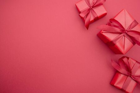 Red gift boxes and ribbon bows, isolated on red background with red bow. Top view. Copy space. Christmas, Party or Valentin's Day.の写真素材