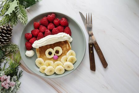 Fun food for kids. Christmas Santa pancake with raspberry and banana for children menu, top view with copy space for text.の写真素材