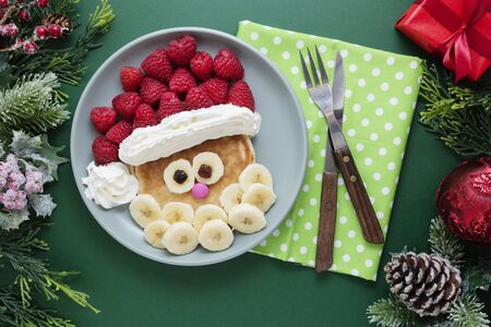 Fun food for kids. Christmas Santa pancake with raspberry and banana for children menu, top view with copy space for text.の写真素材