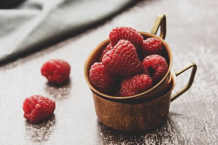 Fresh raspberries close up in metal cups. Concept for healthy nutrition lifestyle. Toned image with dark background.の写真素材