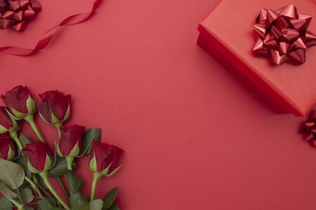 Red roses and gift box with ribbon, over red background flat lay. Valentine's Day, Birthday abstract background with copy space. for text.の写真素材