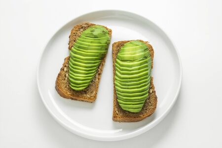 Avocado slices on white background. Avocado toast in white round plate isolated on white.の写真素材