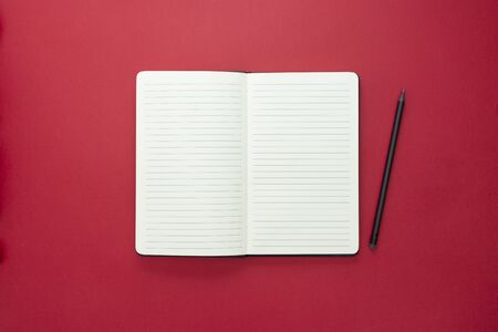 Open notebook isolated on red background, copy space for message.の写真素材