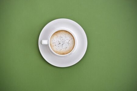 Top view hot latte coffee in white cup. Isolated on green background. Copy space for text.の写真素材