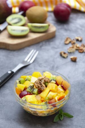 Fresh fruits salad in glass bowl - mango, citrus, kiwi fruit, plum and persimmon. Healthy food.の写真素材