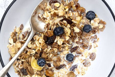 Whole oats breakfast, granola with dried fruit and blueberry, milk and honey. Healthy food, clean...