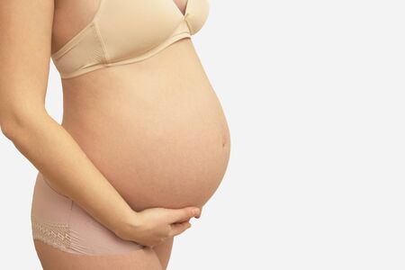 Beautiful pregnant belly close up. Expecting a baby, pregnancy and motherhood. Copy space for text.