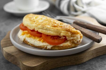 Omelet with cheese and tomatoes and a cup of coffee. Healthy homemade omelette for breakfast. Dark background.の写真素材