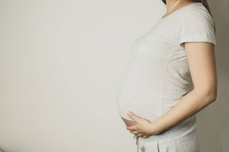Pregnant woman with her hands on her belly, close up, copy space for text.