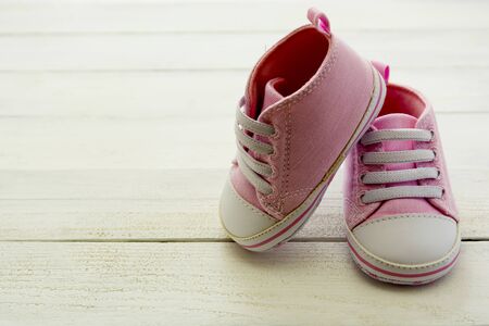 Pink baby girl shoes, on gray background. Newborn, motherhood, pregnancy concept with copy space for...