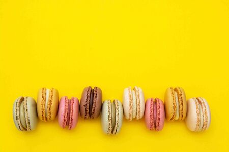 Colorful abstract background with traditional french macaroons cookies, over yellow background with...