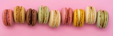 Colorful traditional french macaroons cookies on pink
