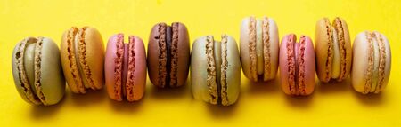 Colorful abstract background with traditional french macaroons cookies, over yellow background...