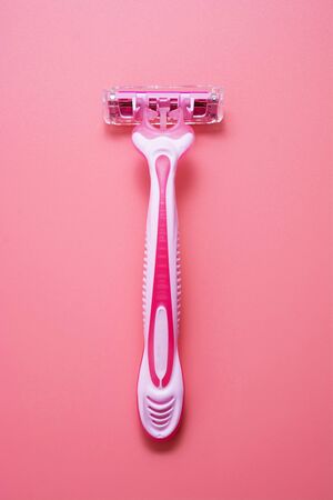 Woman pink plastic razor isolated on pink background. Disposable female shavers. Skin care.の写真素材