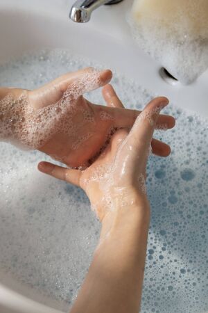 Close up of child's hand wash his hands over sink in bathroom.