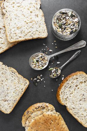 Healthy bread slices on dark background with mix of seeds, top view.の写真素材